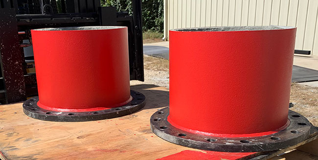 Two red concrete-pressure-pipe components with black flanges on a worktable